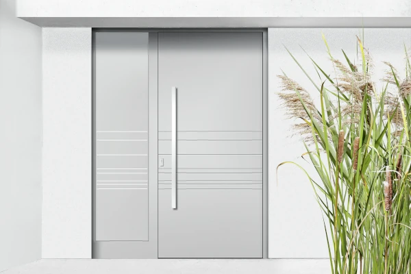 Moderne WIRUS Haustür in elegantem Grau mit klaren Linien und langem, vertikalem Edelstahlgriff; minimalistische Gestaltung mit dezenten Zierelementen, daneben dekorative Gräser im Eingangsbereich.